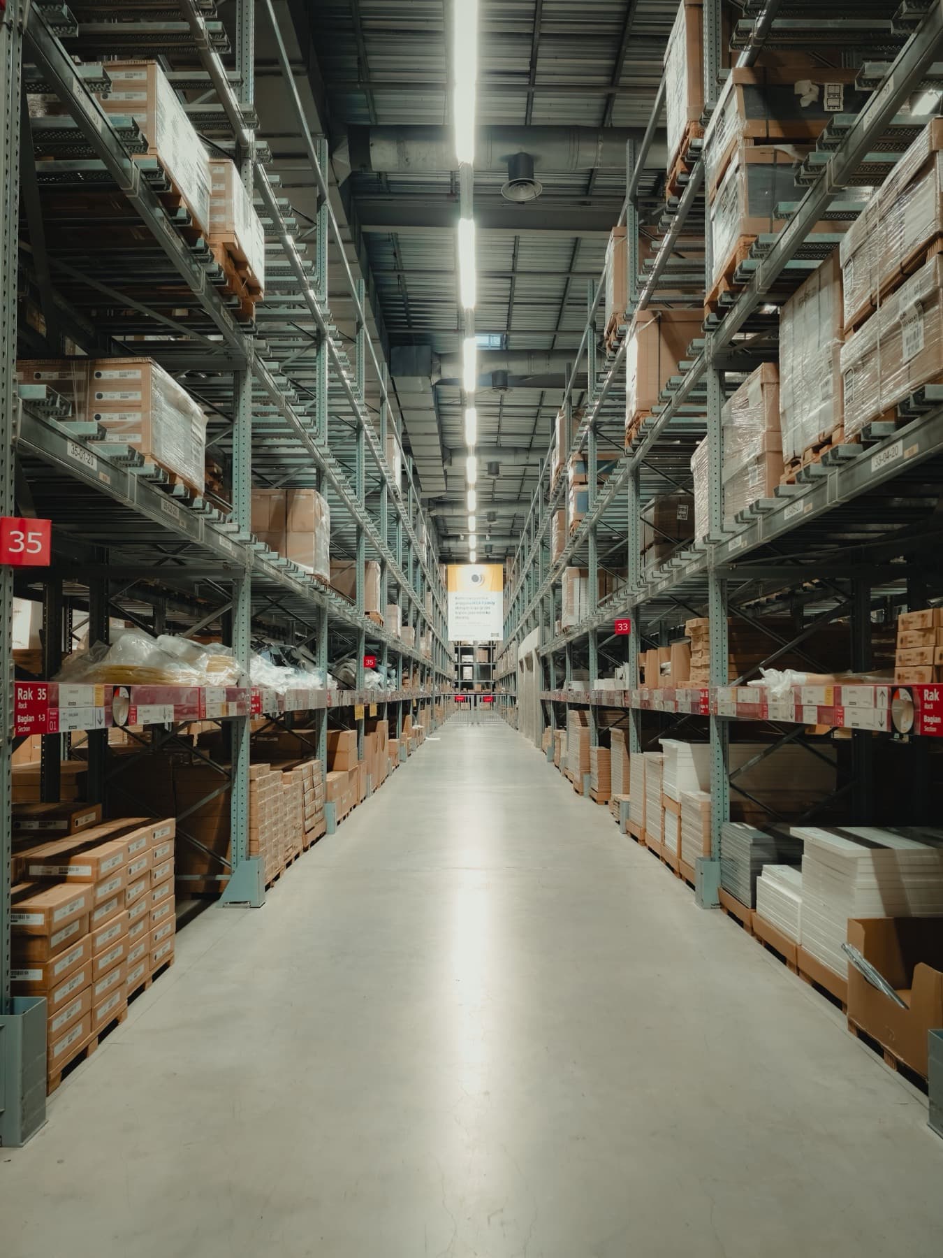 Continuous LED linear fixture lighting a warehouse aisle between high racking